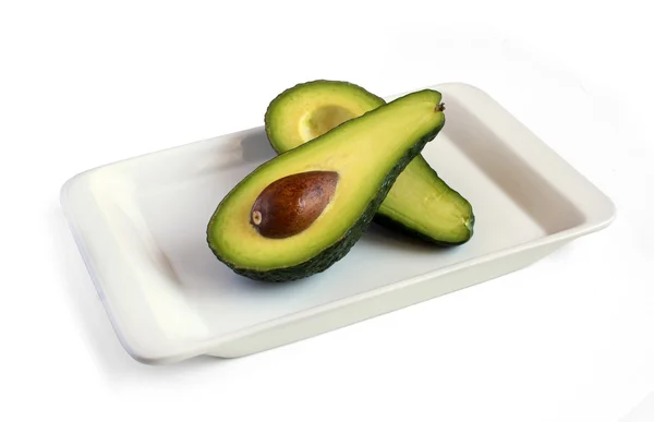 Свежий авокадо разрезанный пополам на квадратной тарелке — стоковое фото