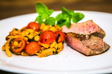 Fasulye salatası ve domatesli bonfile biftek. Restorandaki yemek. Yemek tasarımı ve restoran yemeği.