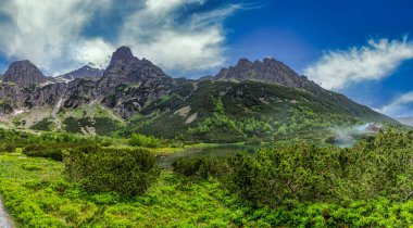 Tarihi dağ kulübesi ve kristal berrak turkuaz suya yansıyan pürüzsüz granit tepeleriyle Zelene pleso 'nun (Yeşil Göl) göz kamaştırıcı geniş manzarası. Yüksek Tatras Ulusal Parkı, Slovakya.