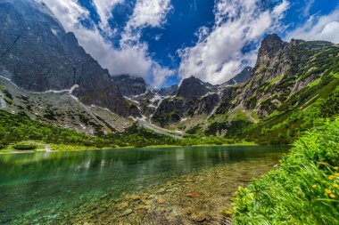 Tarihi dağ kulübesi ve kristal berrak turkuaz suya yansıyan pürüzsüz granit tepeleriyle Zelene pleso 'nun (Yeşil Göl) göz kamaştırıcı geniş manzarası. Yüksek Tatras Ulusal Parkı, Slovakya.
