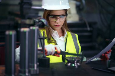 Üretim faktörü üreten makine üretim hattını denetleyen kadın fabrika işçisi.