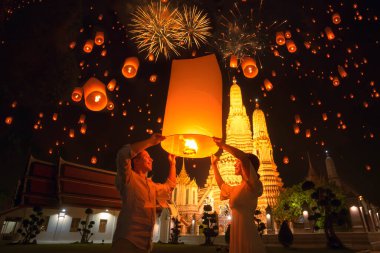 Gezgin çift, Bangkok, Tayland 'daki Arun Tapınağı' ndaki loi kratong festivalinde yüzen fenerin keyfini çıkarıyor.
