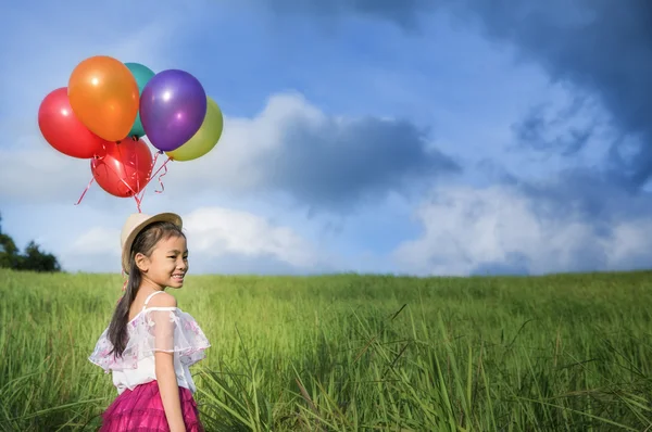 Junges asiatisches Mädchen hält sich fest an ein großes Bündel Helium gefüllt — Stockfoto