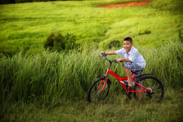 Азиатский мальчик едет на велосипеде — стоковое фото