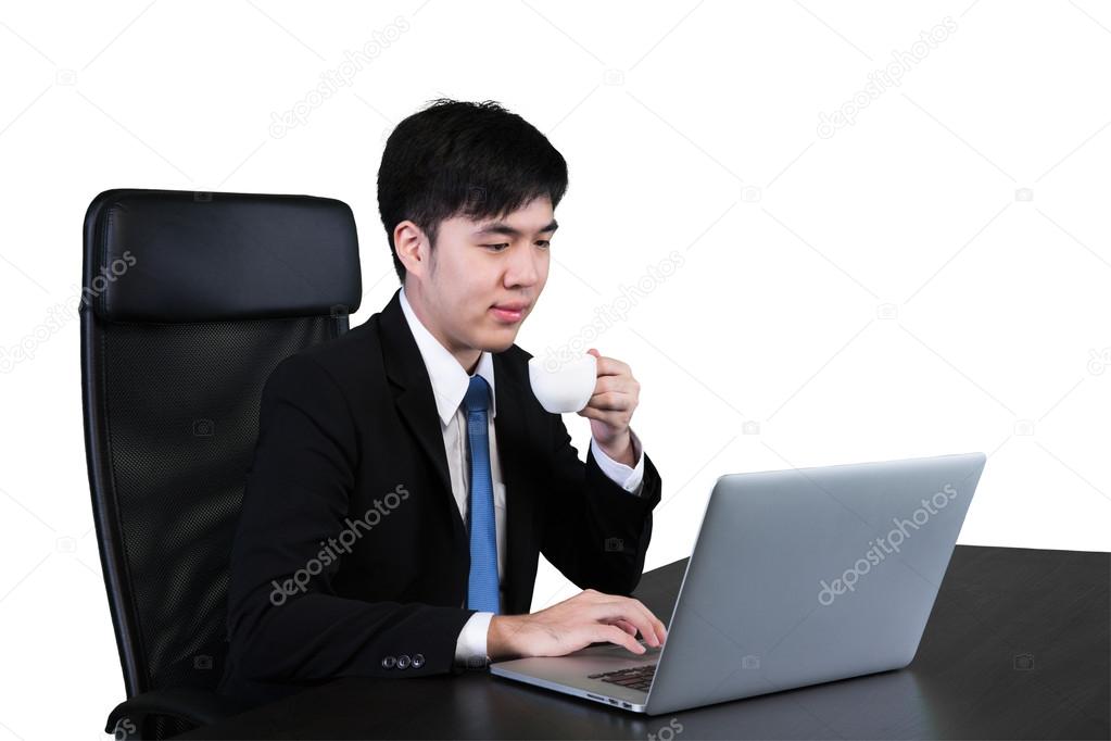 Businessman drinking coffee & tea and using computer