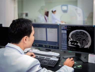 Medical team operating computers in CT scan lab clipart