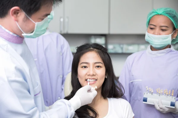 Dentist comparing patient's teeth shade — Stock Photo, Image