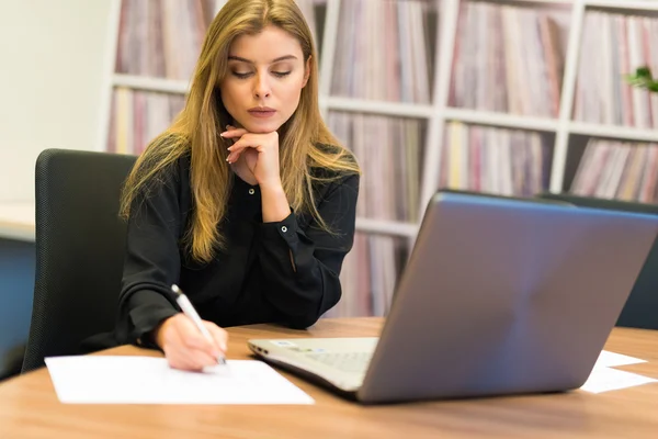 Mulher usando laptop e escrita — Fotografia de Stock