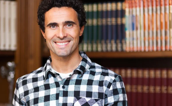 Hombre sonriente en la biblioteca — Foto de Stock