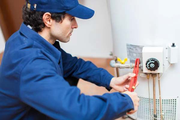 Plumber fixing an hot-water heater Royalty Free Stock Photos