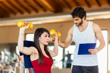 kadın için bir egzersiz açıklayan eğitmen