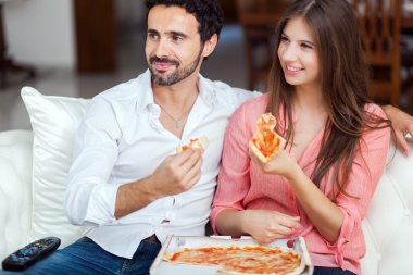 Çift kanepede pizza yemek