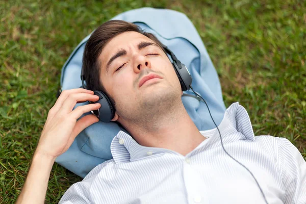 Mann som hører musikk på gress – stockfoto