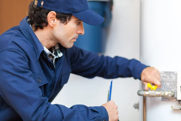 Loodgieter op het werk met warm water kachel — Stockfoto