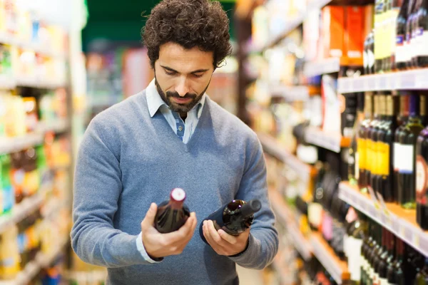 Homem no supermercado escolhendo vinho — Fotografia de Stock
