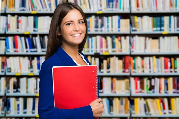 Mulher segurando notebook na biblioteca — Fotografia de Stock