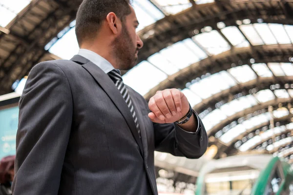 Pendler schaut auf seine Uhr, während er auf seinen Zug wartet. geringe Schärfentiefe, Fokus auf die Hand — Stockbild Pendler schaut auf wartenden Zug — Stockfoto