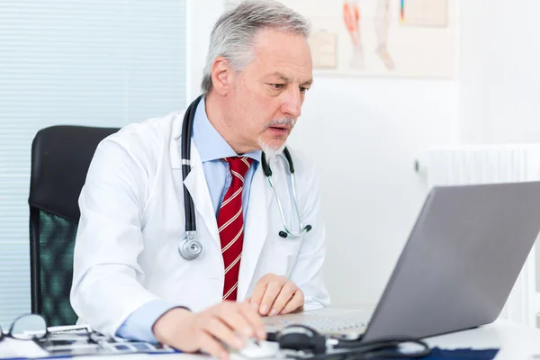 Medico senior che lavora al computer portatile — Foto Stock