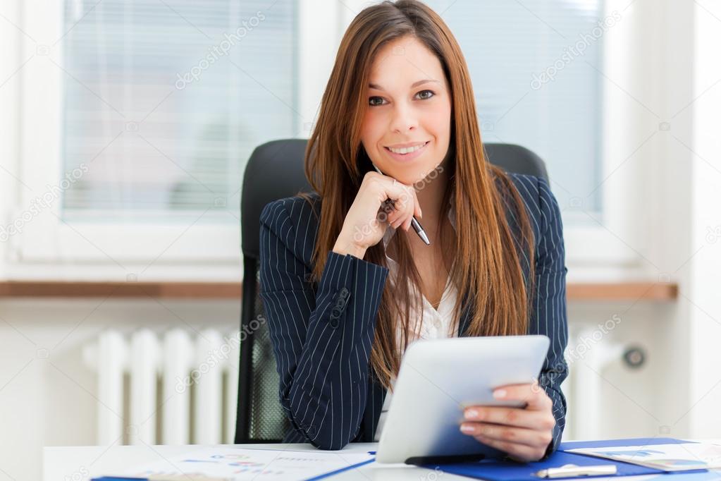 businesswoman holding tablet while sitting at office