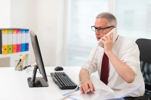 Homme d'affaires au téléphone assis à l'ordinateur — Photo