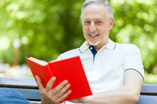 Starší muž čte knihu — Stock fotografie