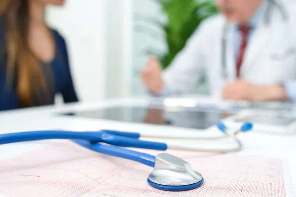 Stethoscope on an electrocardiogram, doctor and patient — Stock Photo, Image