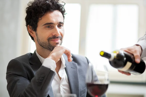 Garçom derramando vinho para o homem — Fotografia de Stock