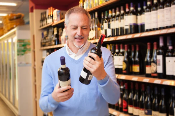 Mann vergleicht zwei Weinflaschen — Stockfoto