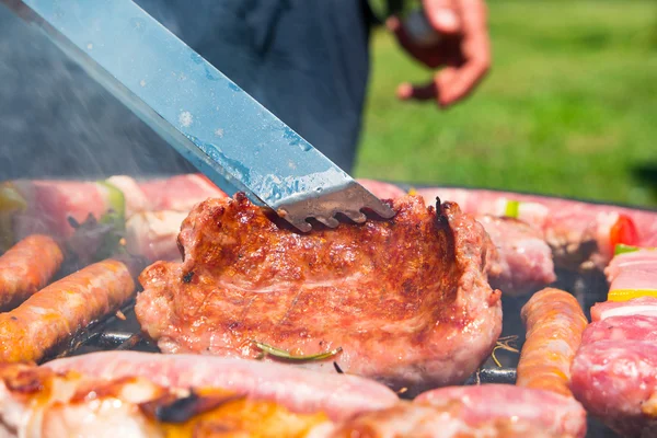 Homem preparando carne na churrasqueira — Fotografia de Stock