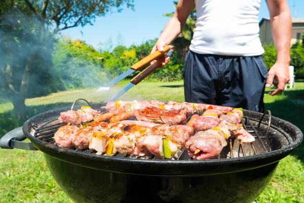 Hombre preparando carne en una parrilla de barbacoa — Foto de Stock