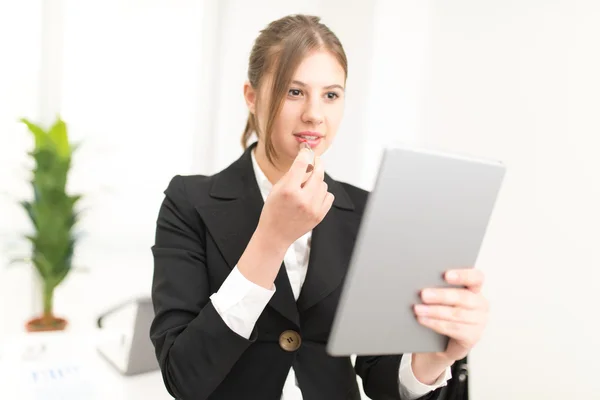 Vrouw met behulp van de tablet te zetten lippenstift — Stockfoto