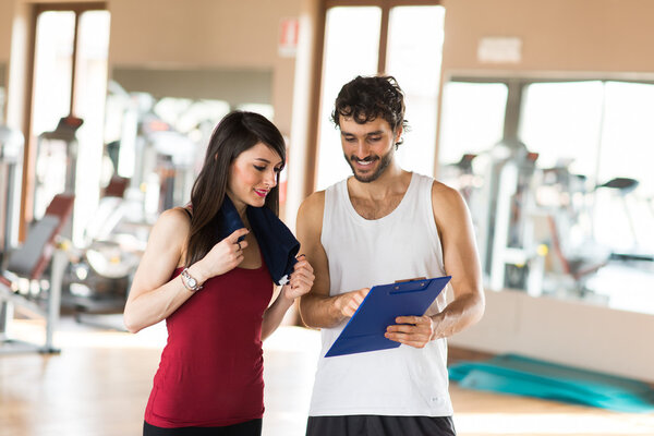 Тренер, объясняющий женщине упражнение
