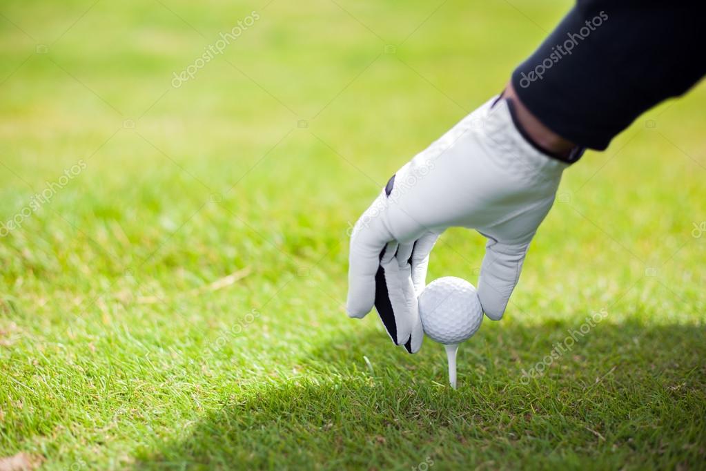 Hand hold golf ball with tee on course Stock Photo by ©minervastock