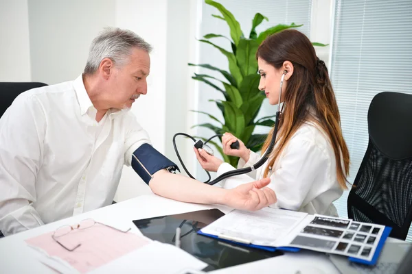 Läkare kontrollerar en patientens blodtryck — Stockfoto