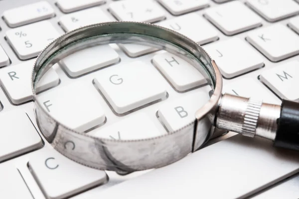 Hand lens on keyboard — Stock Photo, Image