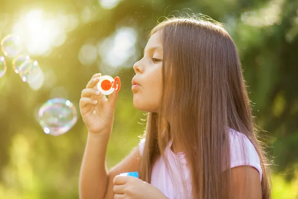 Дитина дме мильні бульбашки на відкритому повітрі — стокове фото