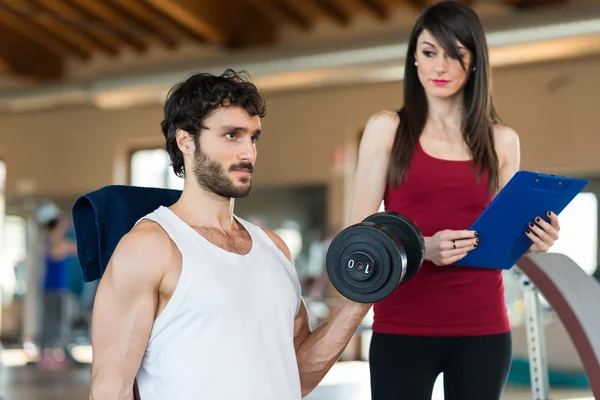 Entrenador mirando al hombre haciendo un ejercicio — Foto de Stock