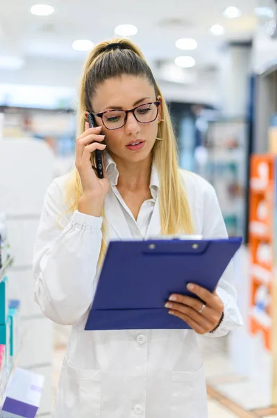 Női Gyógyszerész Beszél Telefonon Egy Vásárlóval Boltjában — Stock Fotó