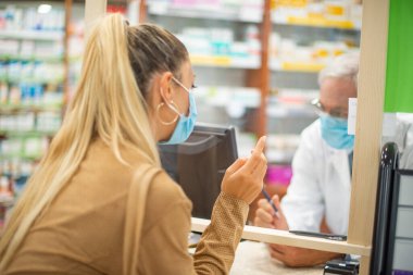 Genç maskeli kadın eczaneye giriş yapıyor. Coronavirus konsepti.