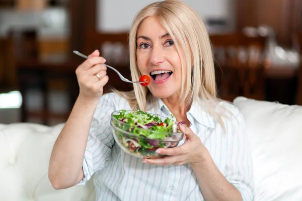 Reife Frau Isst Einen Gesunden Salat Auf Ihrem Sofa — Stockfoto