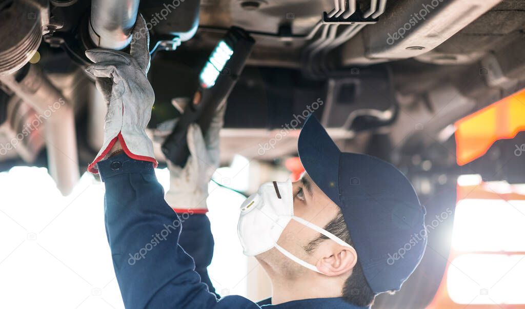 Portrait of a mechanic repairing a car in his garage, covid coronavirus concept