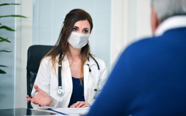 Maskeli doktor bir hastayla konuşuyor, Coronavirus covid konsepti.