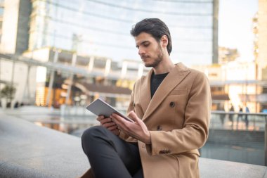 Genç adam tabletini şehir dışında kullanıyor.