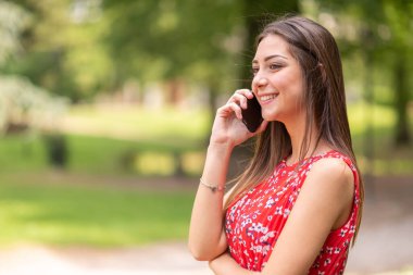 Gülümseyen genç kadın cep telefonuyla konuşuyor.