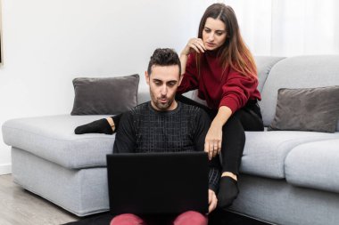 Evlerinde dizüstü bilgisayar kullanan mutlu bir çiftin portresi.