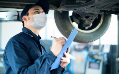 Maskeli araba tamircisi araba tamir ediyor, koronavirüs çalışma konsepti