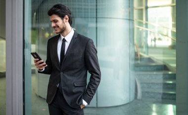 İş adamı iş ortamında akıllı telefonunda uygulama kullanıyor.