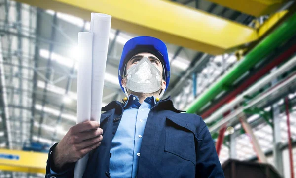 Portrait of a masked industrial worker in a factory, covid coronavirus concept