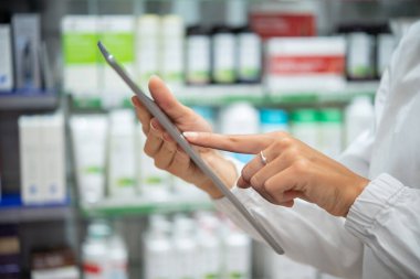 Kadın eczacı eczanedeki envanteri kontrol ediyor.