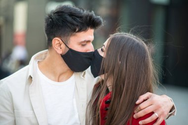 Covid ya da Coronavirus maskesi takarken öpüşen çift, salgın aşk konsepti